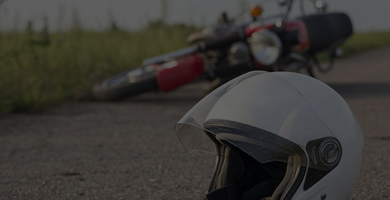 Capacete de motociclista caído no chão, atrás moto tombada para o lado