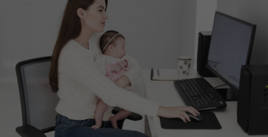 Mulher com bebê no colo trabalhando em home office