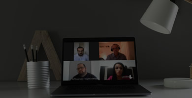 Laptop sobre a mesa, na tela é exibido um vídeo de um debate entre quatro participantes