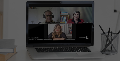 Computador sobre a mesa, na tela imagem de um homem e duas mulheres em uma reunião em vídeo